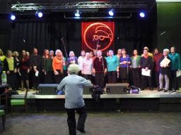 Blurred picture of the choir dancing during a performance with Jules also dancing in the foreground March 2010